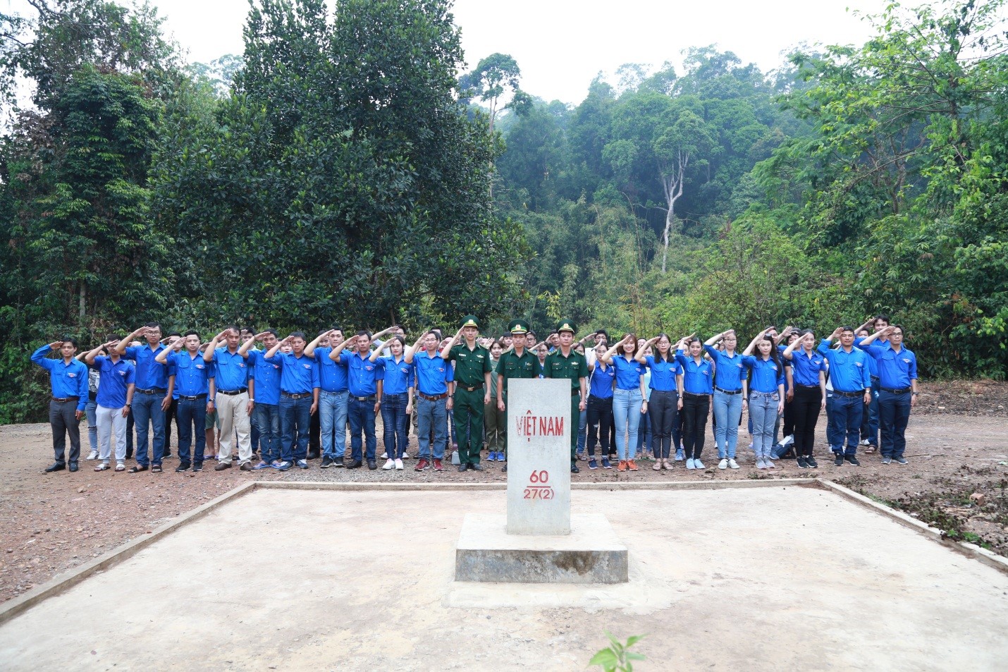 Đoàn thanh niên đứng chào nghiêm trang trước cột mốc thiêng liêng